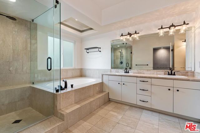 a bathroom with a bathtub shower sink and mirror