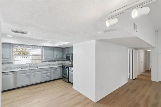 a kitchen with white cabinets and wooden floor