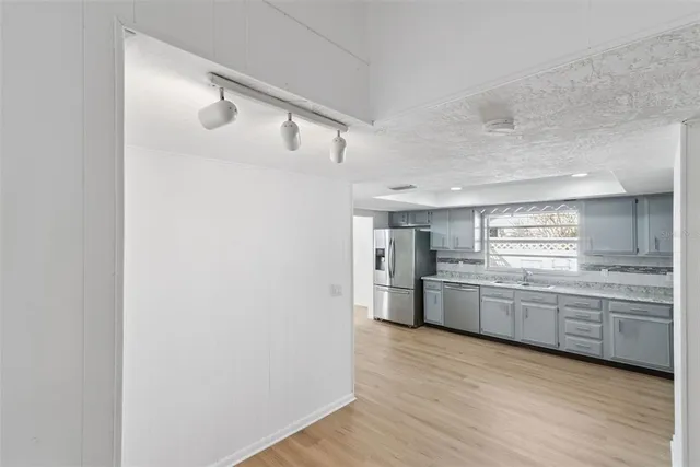 a kitchen with stainless steel appliances granite countertop a refrigerator a sink dishwasher a oven and white cabinets with wooden floor