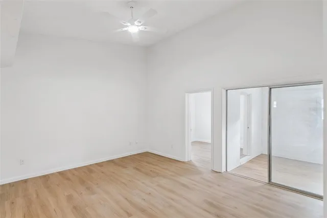 an empty room with wooden floor and ceiling fan