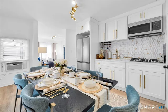 a dining room with furniture a flat screen tv and kitchen view