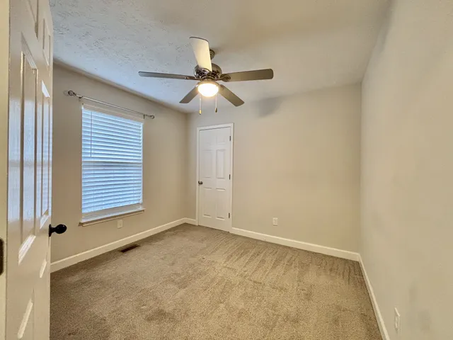 an empty room with windows and fan