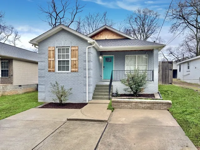 a front view of a house with a yard and potted plants