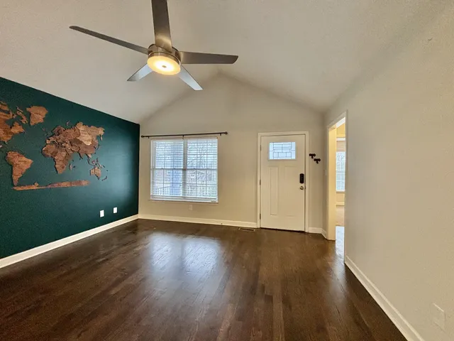 an empty room with wooden floor chandelier fan and windows