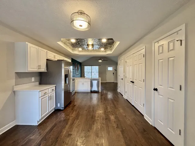 a large kitchen with kitchen island granite countertop wooden floors and a view of living room