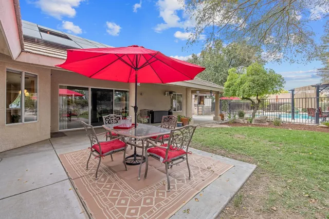 a view of a backyard with table and chairs potted plants and large tree