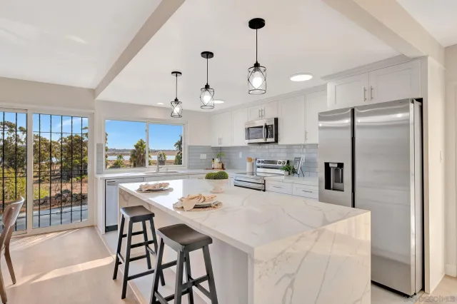 a kitchen with stainless steel appliances kitchen island granite countertop a table chairs refrigerator and microwave