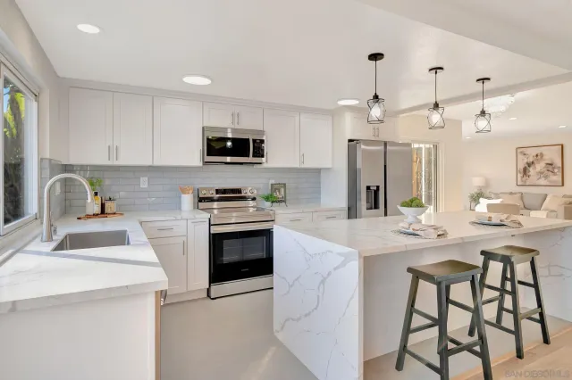 a kitchen with kitchen island granite countertop a sink a counter space appliances and cabinets