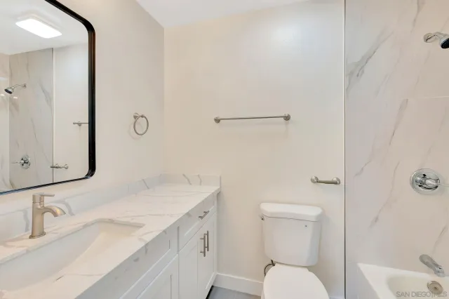 a bathroom with a granite countertop sink mirror vanity and toilet
