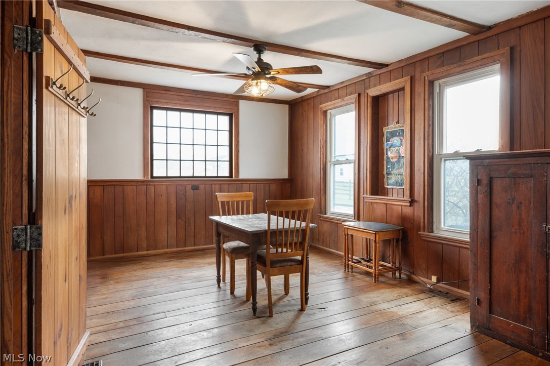 9455 Robinson Road Chardon, OH 44024 - Photo 15 of 33 Dining space with wood walls, a wainscoted wall, beam ceiling, a ceiling fan, and light wood-style flooring