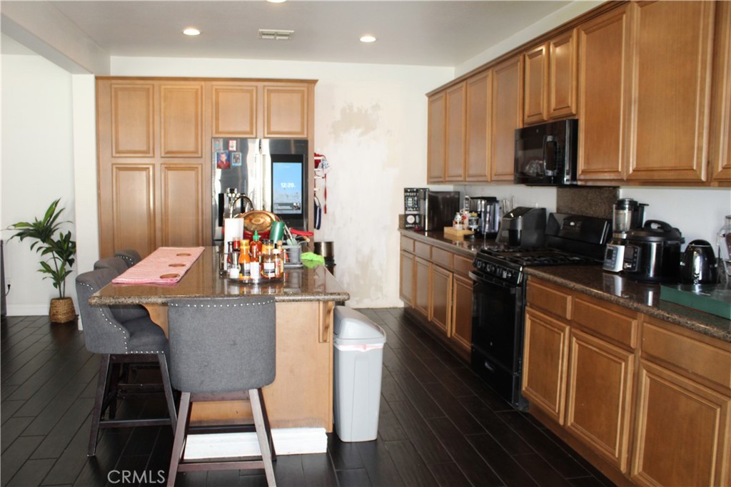 1382 Sunset Avenue Perris, CA 92571 - Photo 4 of 23 a kitchen with stainless steel appliances kitchen island granite countertop a refrigerator a stove a sink dishwasher and white cabinets with wooden floor