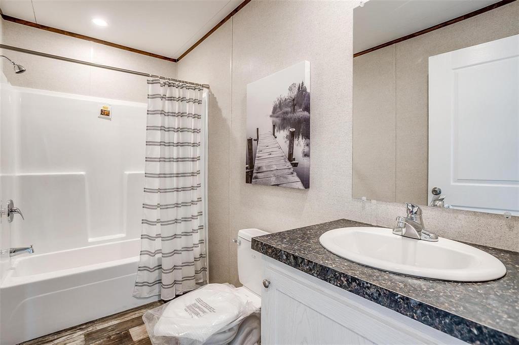 242 Huddleston Road Sunset, TX 76270 - Photo 13 of 18 a bathroom with a granite countertop sink a toilet and shower