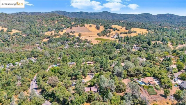 an aerial view of residential house with outdoor space and trees all around