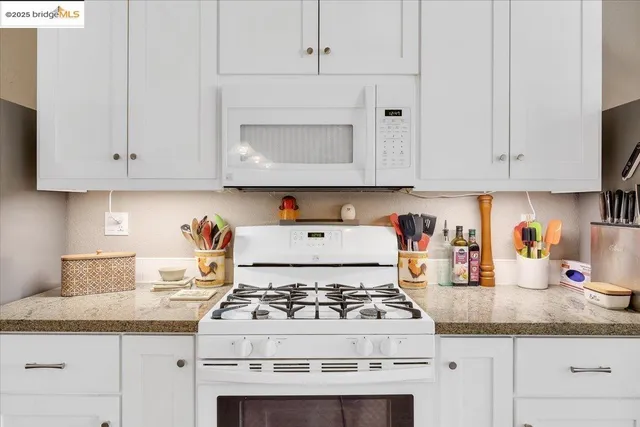 a kitchen with stainless steel appliances granite countertop a stove and white cabinets
