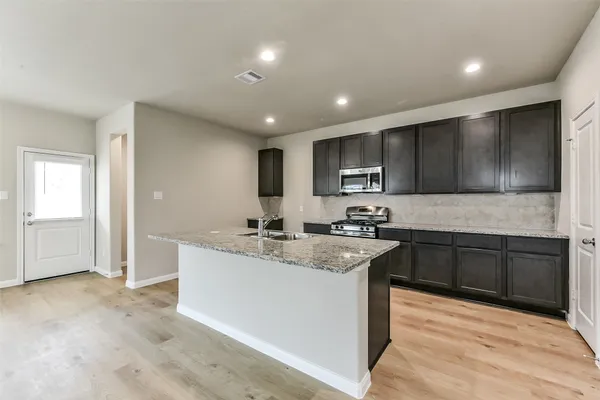 a kitchen with stainless steel appliances granite countertop a sink stove refrigerator and cabinets