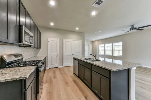 a kitchen with granite countertop kitchen island stainless steel appliances a sink stove top oven and cabinets