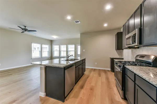 a kitchen with granite countertop kitchen island wooden floors granite counter tops and stainless steel appliances