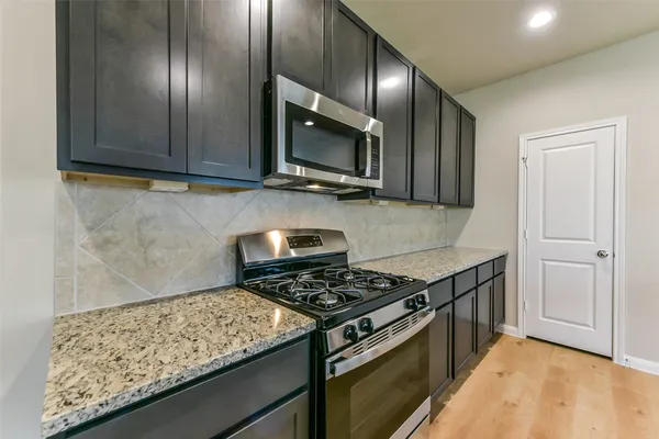 a kitchen with stainless steel appliances granite countertop a stove and a microwave