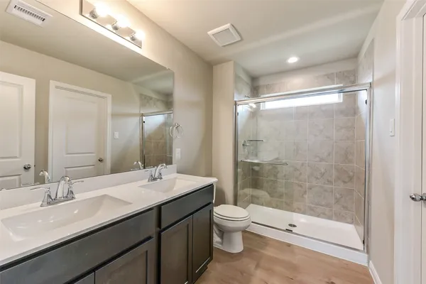 a bathroom with a double vanity sink toilet and shower