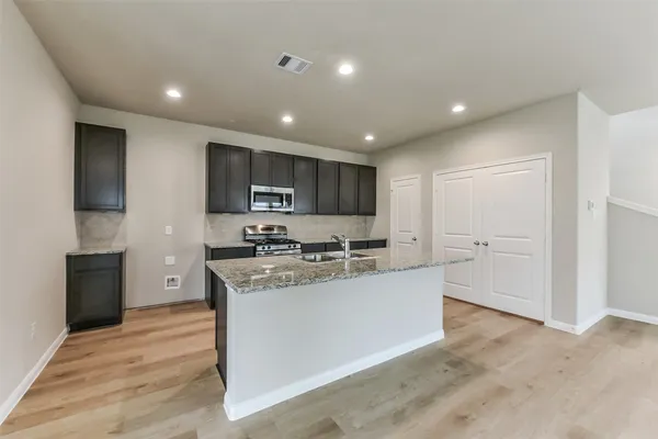 a large kitchen with stainless steel appliances granite countertop a stove a sink and a refrigerator