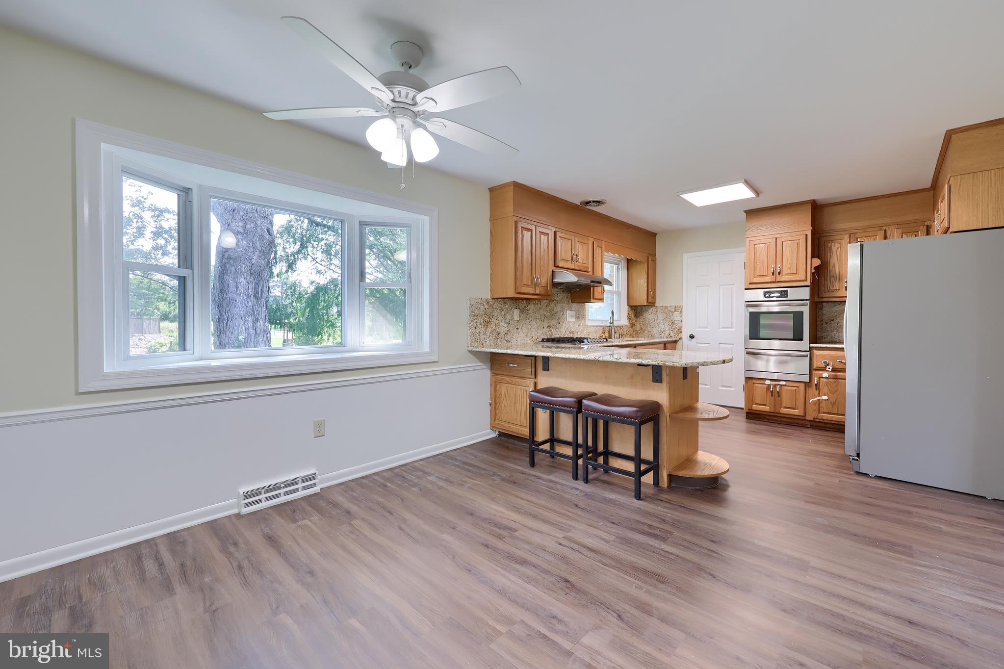 1046 Hunsicker Road Lancaster, PA 17601 - Photo 14 of 31 a open kitchen with stainless steel appliances granite countertop a stove top oven a refrigerator a dining table and chairs with wooden floor
