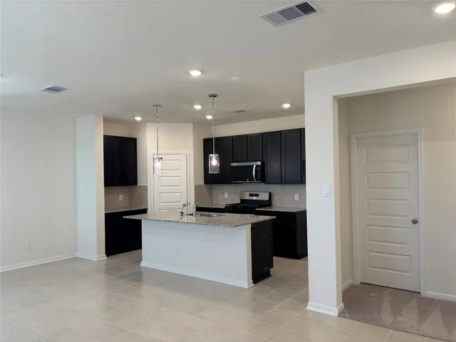 a kitchen with stainless steel appliances kitchen island granite countertop a refrigerator and a stove top oven