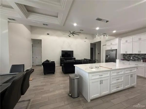 a large white kitchen with a stove a sink dishwasher and a refrigerator with wooden floor