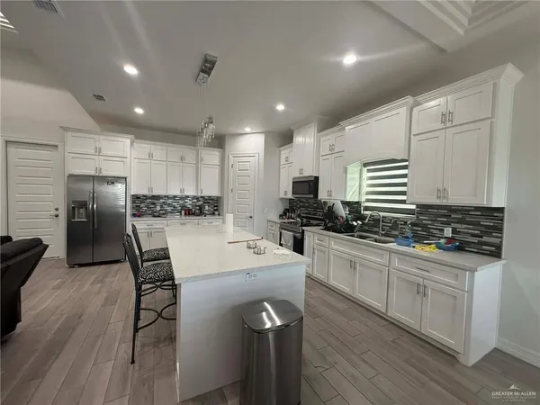 a kitchen with stainless steel appliances a refrigerator sink and white cabinets