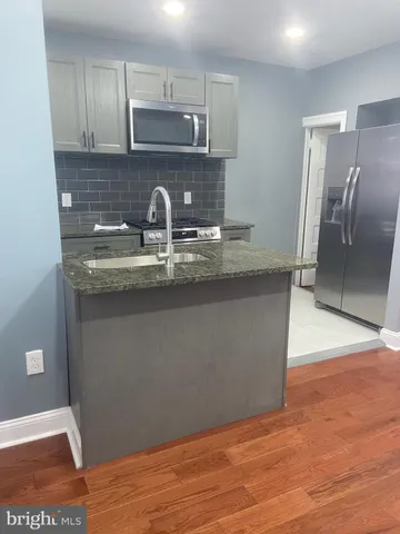 a kitchen with stainless steel appliances granite countertop a sink a stove a refrigerator and cabinets