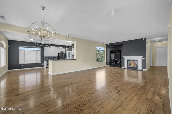 a view of a livingroom with wooden floor and a kitchen space