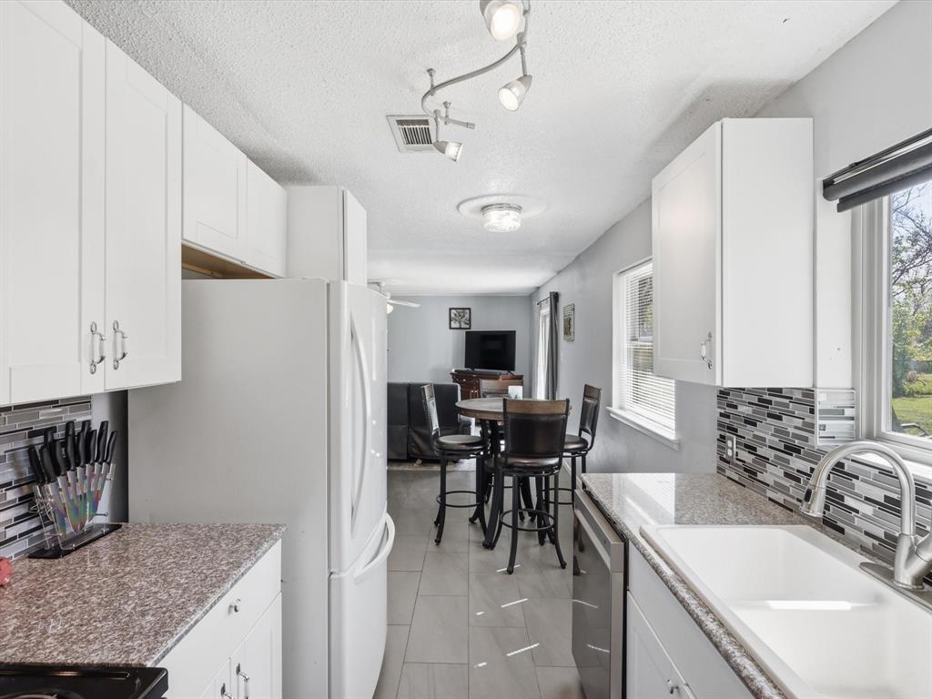 3228 Hummingbird Lane Denton, TX 76209 - Photo 11 of 27 a kitchen with granite countertop a sink a stove a dining table and chairs