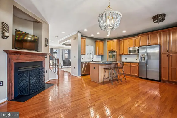 a kitchen with stainless steel appliances granite countertop a refrigerator a oven a stove and a dining table with wooden floor