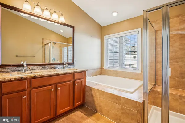 a bathroom with a granite countertop sink and a bathtub