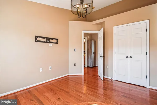 a view of a hallway with wooden floor and chandelier