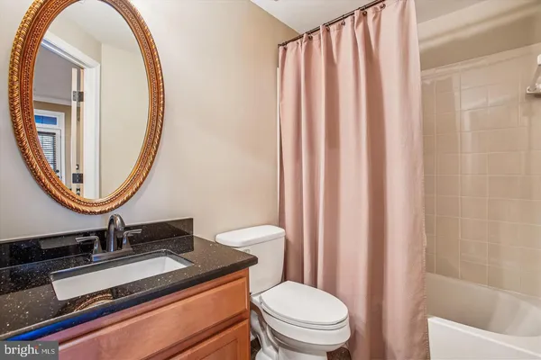 a bathroom with a granite countertop toilet a sink and a mirror