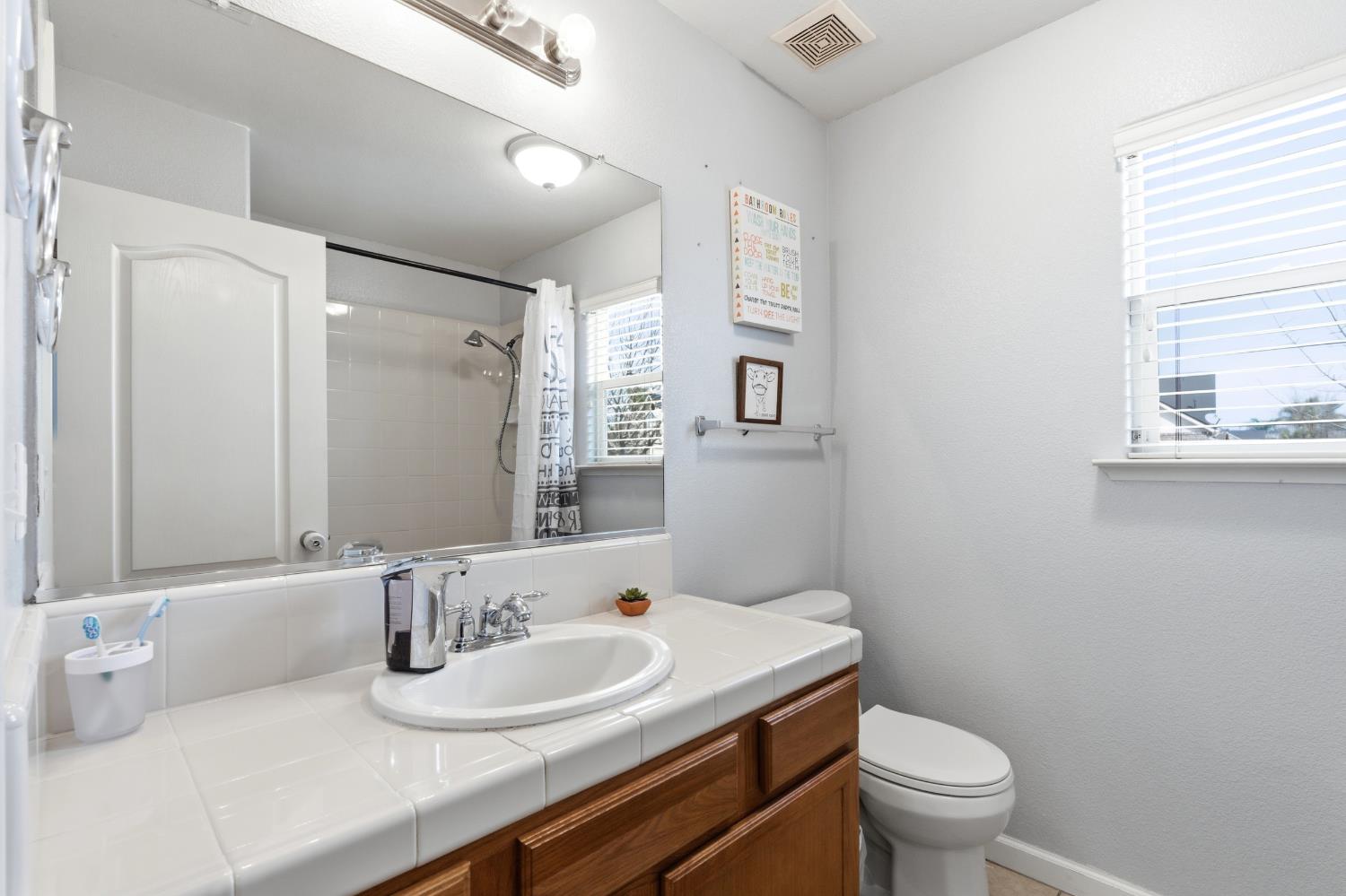 1116 Liberation Way Lemoore, CA 93245 - Photo 20 of 43 a bathroom with a granite countertop toilet a sink and a mirror