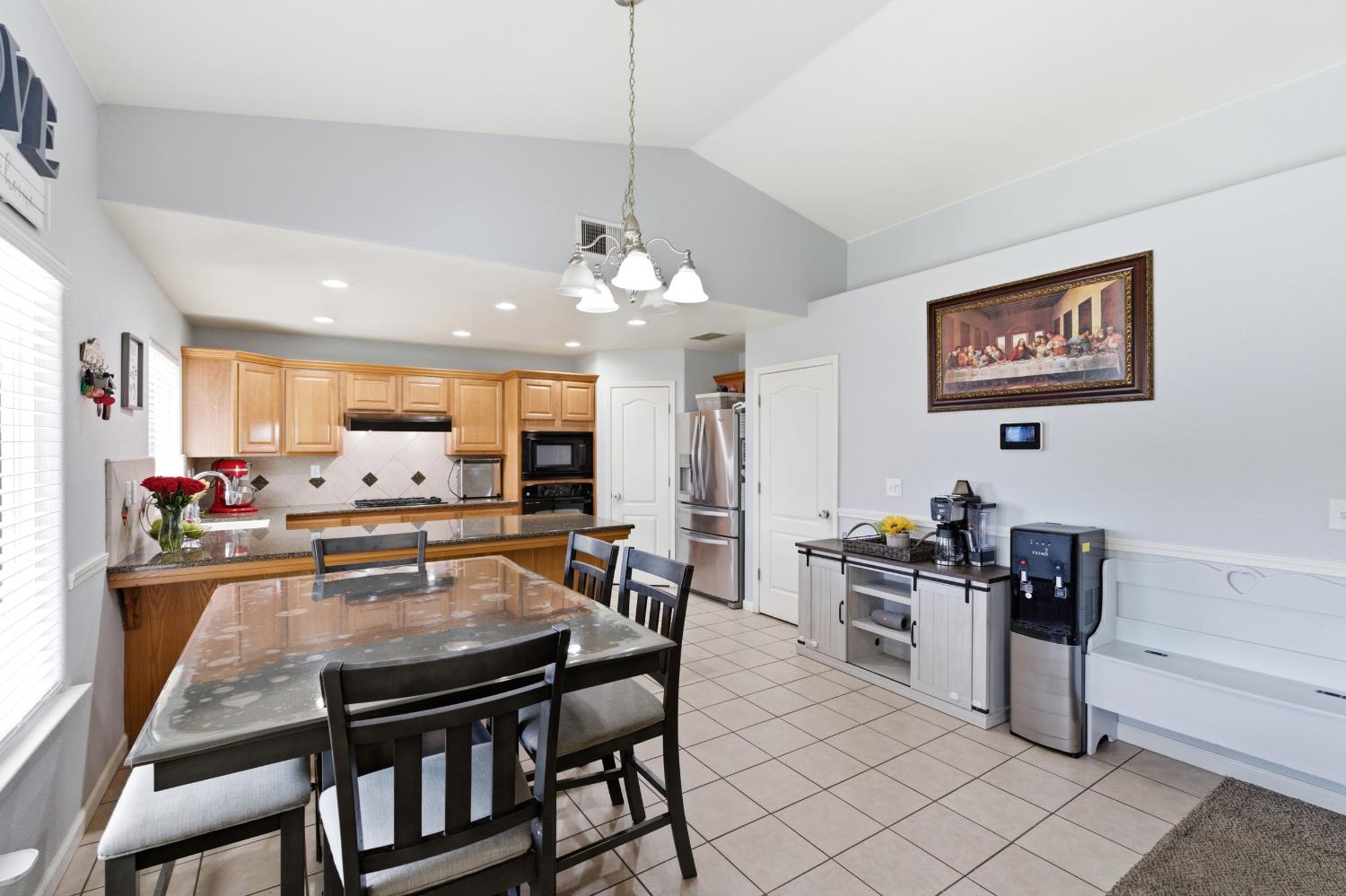1116 Liberation Way Lemoore, CA 93245 - Photo 7 of 43 a kitchen with stainless steel appliances kitchen island granite countertop a stove a refrigerator a dining table and chairs with wooden floor