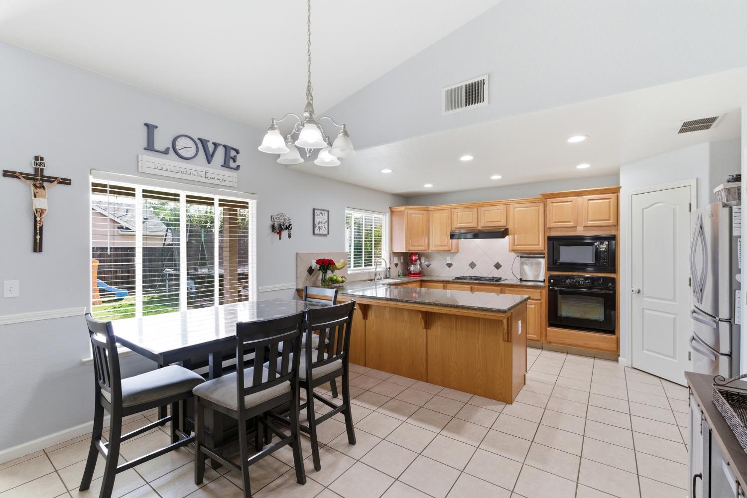1116 Liberation Way Lemoore, CA 93245 - Photo 8 of 43 a kitchen with stainless steel appliances granite countertop a stove top oven a sink dishwasher a dining table and chairs with wooden floor