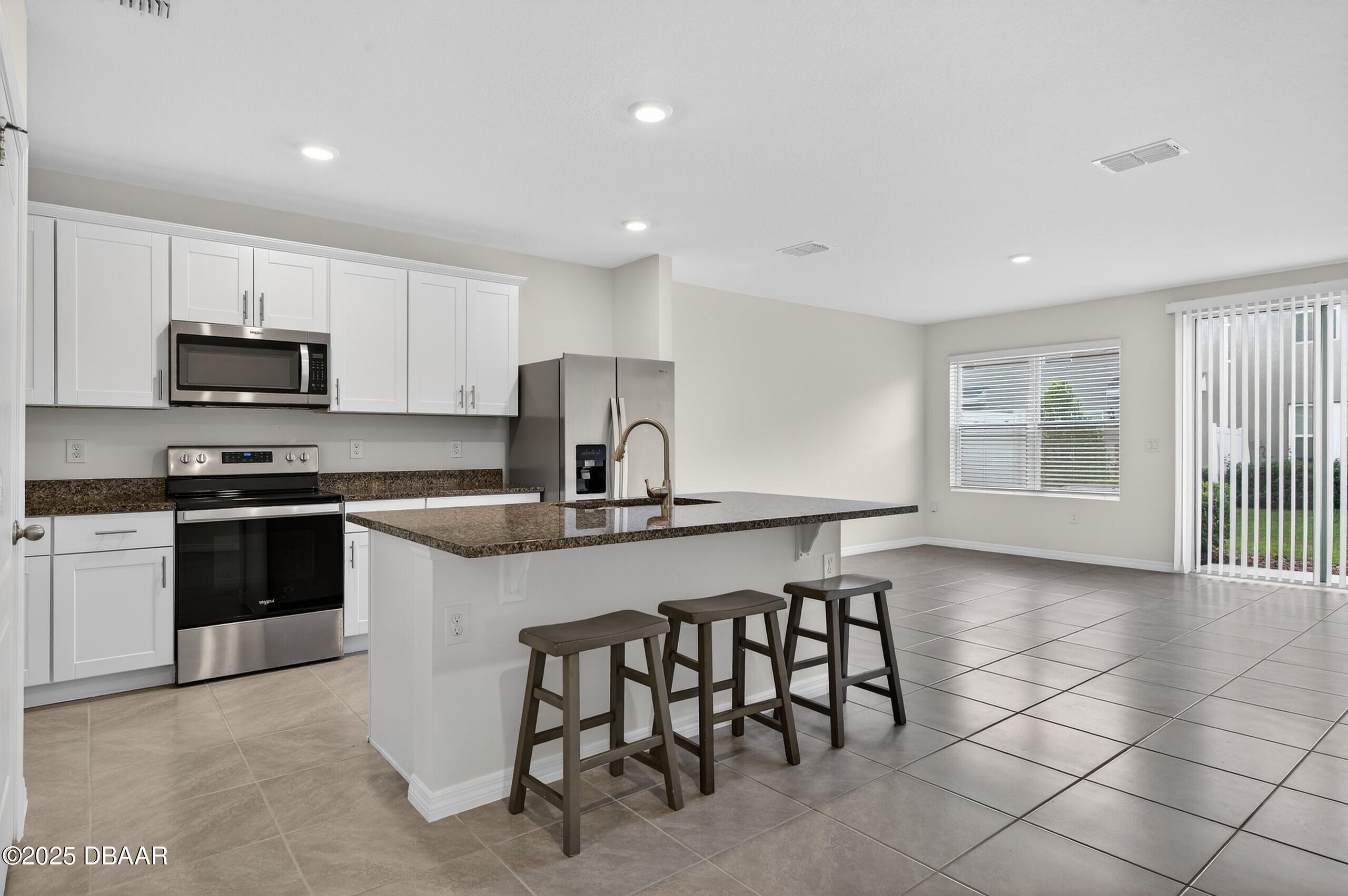 54 Bella Oaks Drive Port Orange, FL 32129 - Photo 6 of 32 a kitchen with stainless steel appliances a stove a sink a microwave a refrigerator and cabinets