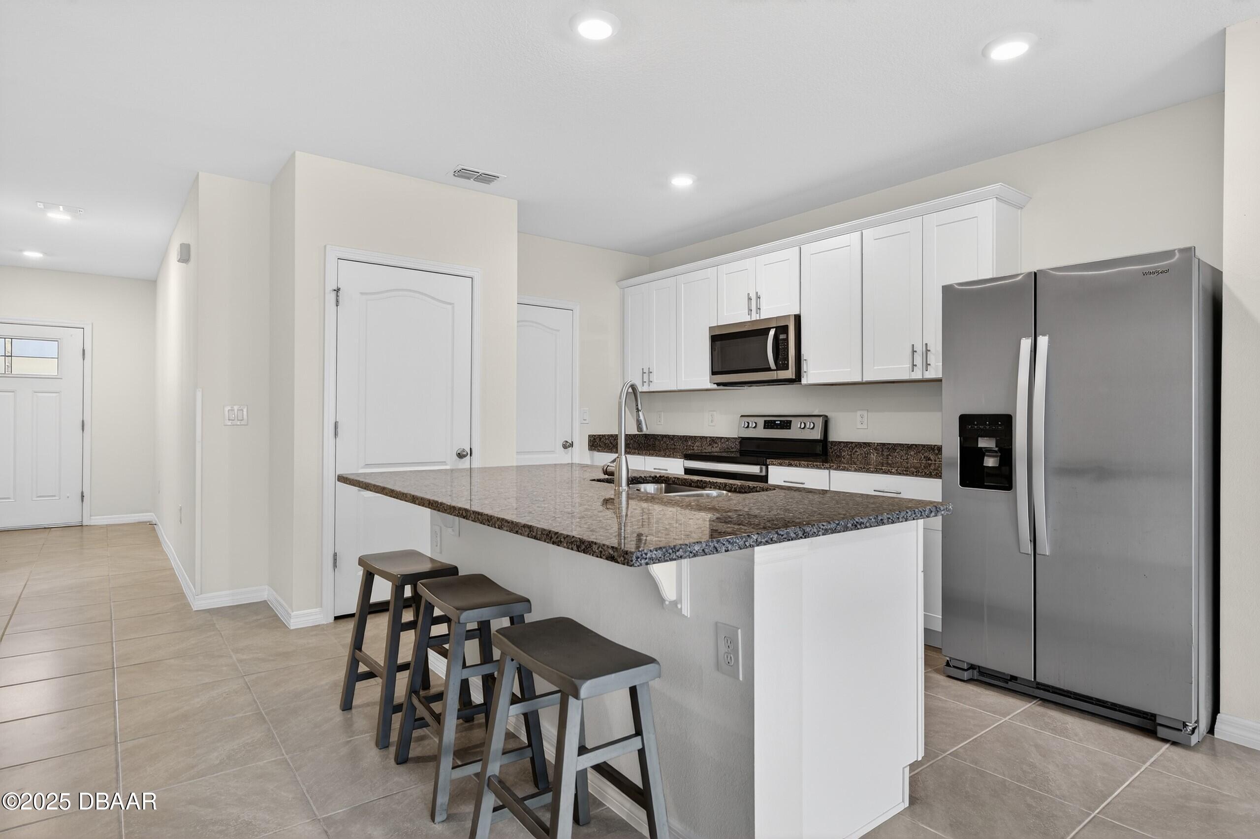 54 Bella Oaks Drive Port Orange, FL 32129 - Photo 7 of 32 a kitchen with stainless steel appliances a refrigerator stove microwave and cabinets
