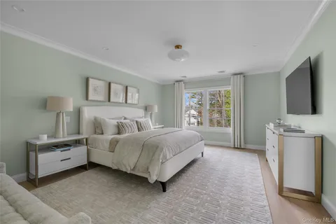 a spacious bedroom with a bed and a flat tv screen on the dresser