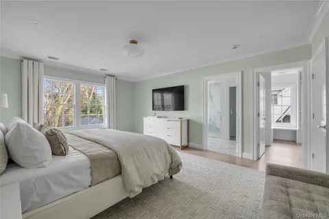 a spacious bedroom with a bed and a flat screen tv