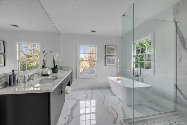 a large bathroom with a granite countertop tub a sink and a large mirror