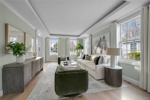 a living room with furniture large window and wooden floor