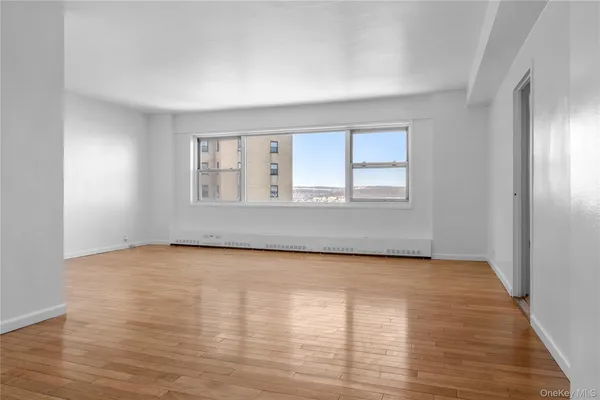 a view of an empty room with wooden floor and a window