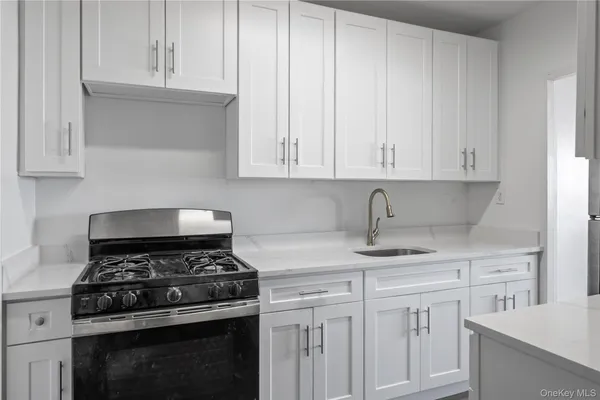 a kitchen with granite countertop white cabinets and stainless steel appliances