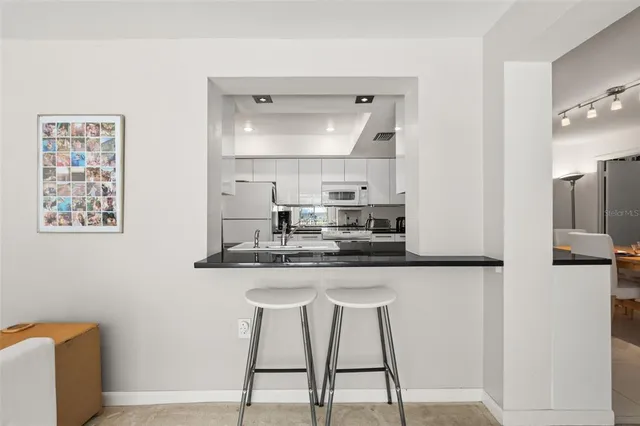 a kitchen with granite countertop a dining table chairs and white cabinets