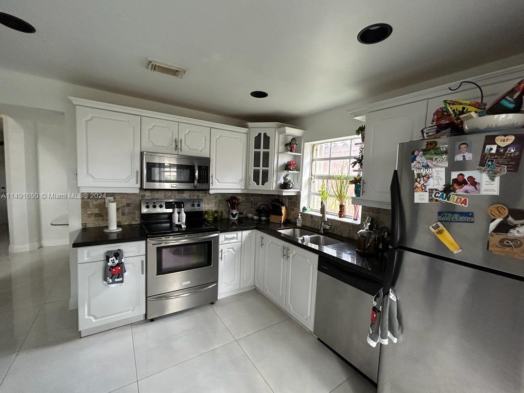 Marbella Park Hialeah, FL 33015 - Photo 20 of 24 a kitchen with stainless steel appliances granite countertop a sink and dishwasher a stove top oven with wooden floor