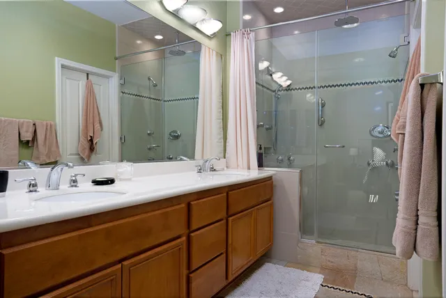 a bathroom with a double vanity sink mirror and shower