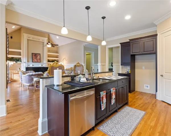 a kitchen with stainless steel appliances granite countertop a sink a stove and a wooden floors